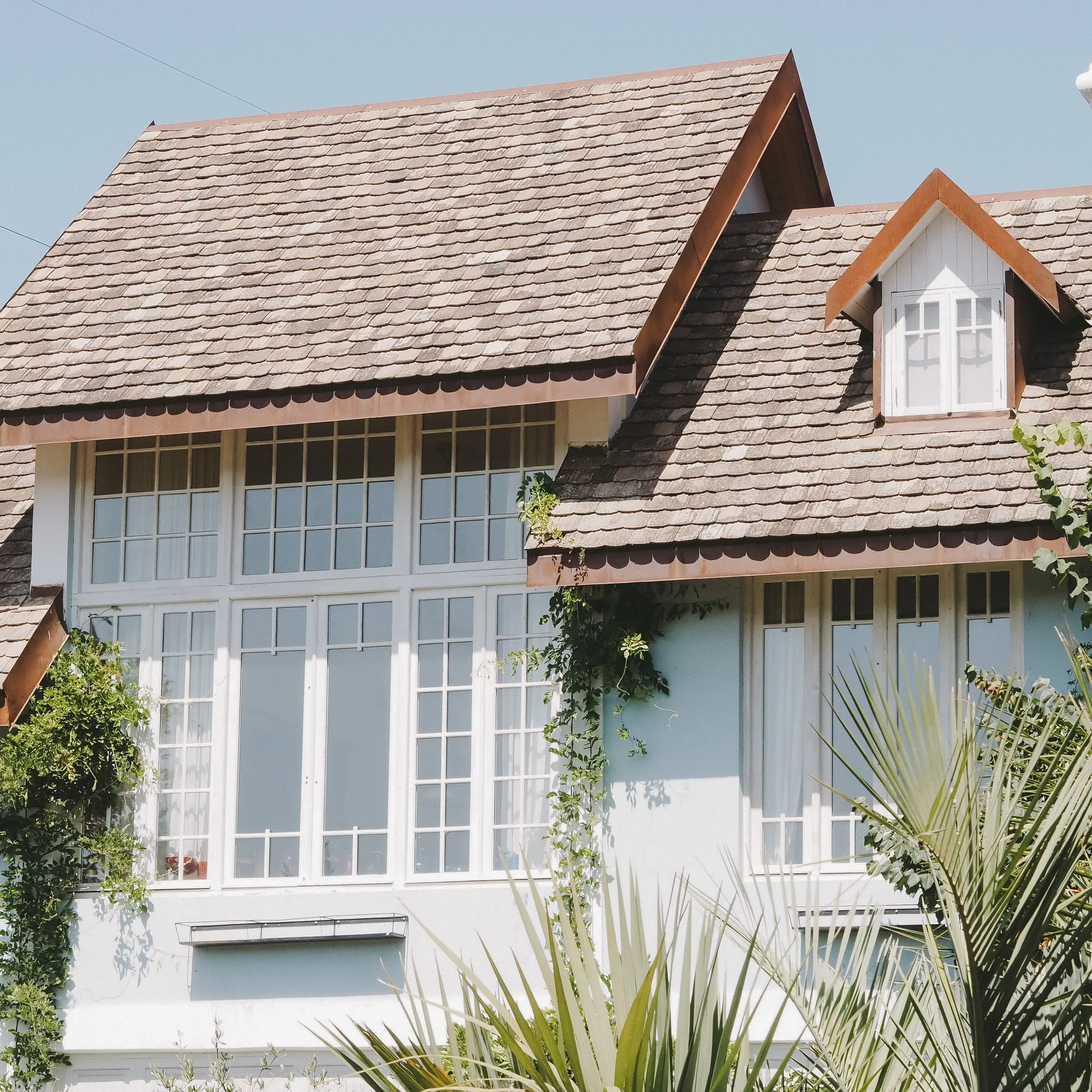 Dormer windows set into a shingle roof in low sunlight
