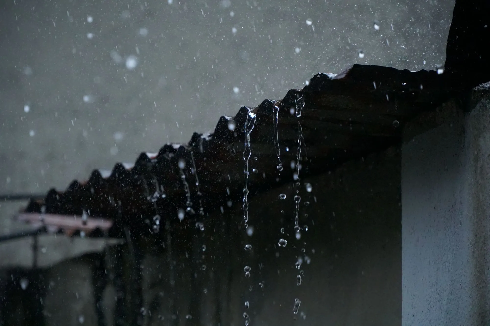 Rain running off the edge of a roof in a heavy shower