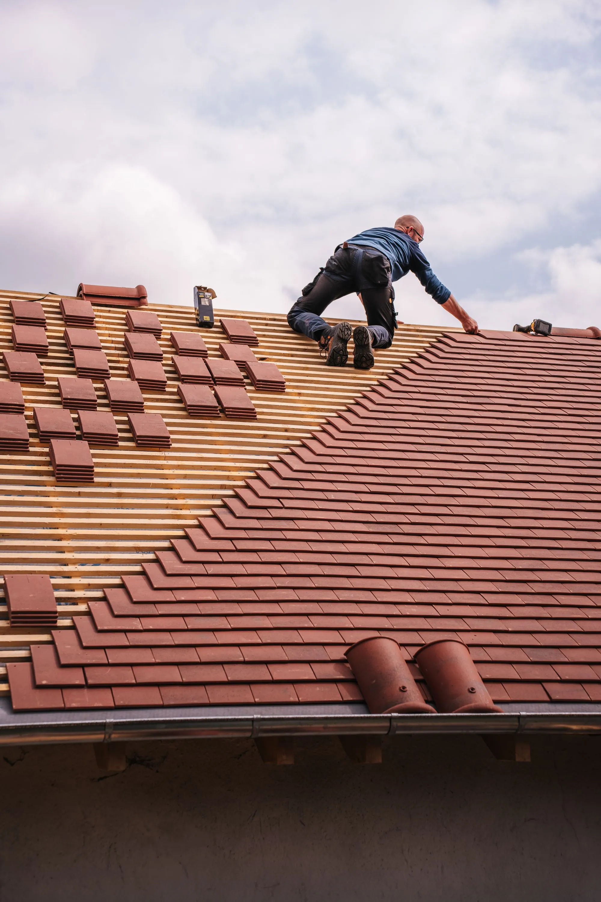 New roof tiles being laid in courses across a roof